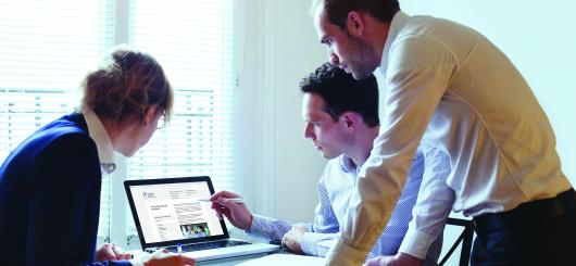 Three people working together and looking at a computer screen.